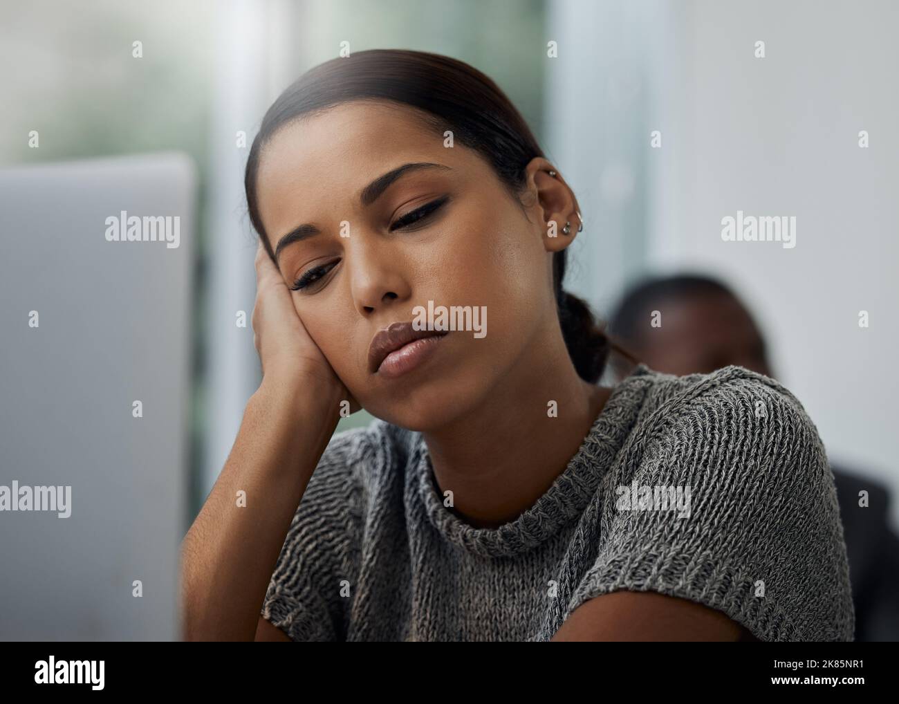 Mann, wenn es 5 Uhr kommt. Eine junge Geschäftsfrau, die an ihrem Schreibtisch gelangweilt aussieht. Stockfoto