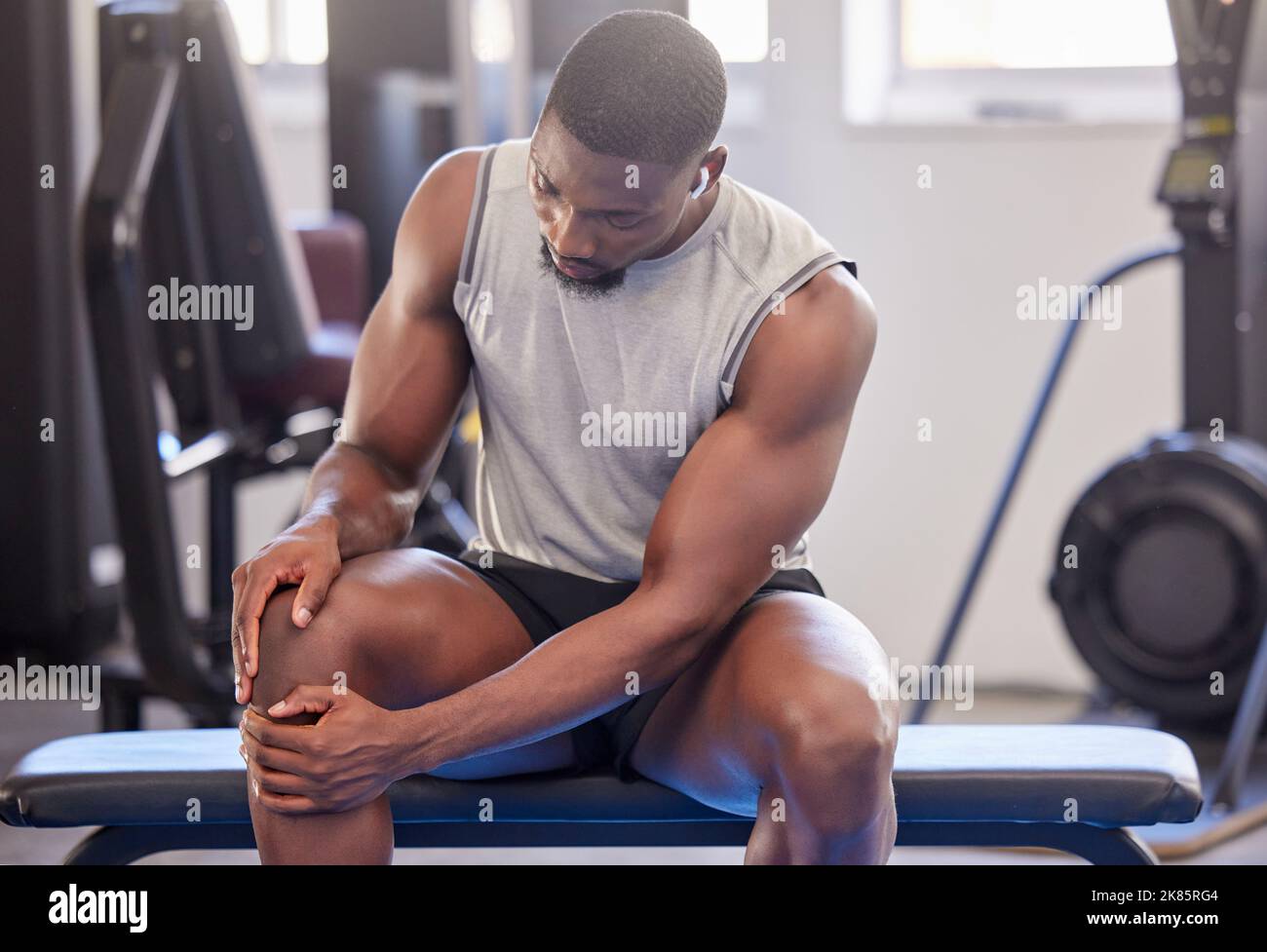 Schwarzer Mann, Fitness und Knieverletzung im Fitnessstudio nach dem Training, Training oder intensiven Übungen. Kopfhörer, Gesundheit und Bodybuilder männlich aus Nigeria leiden Stockfoto