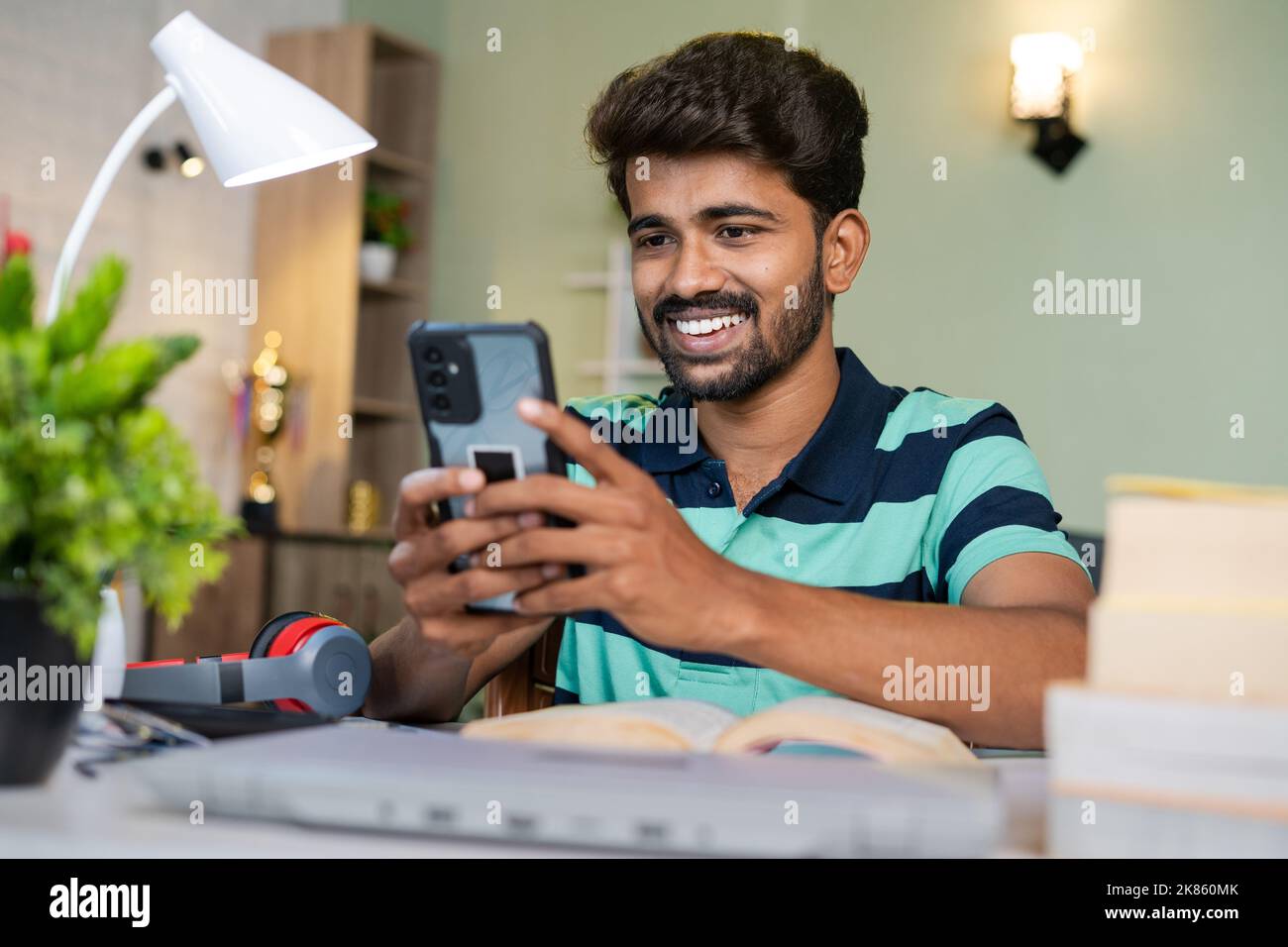Happy Smiling College Student mit Handy beim Lesen am Schreibtisch - Konzept der Entspannung, Pause und Social-Media-sucht Stockfoto