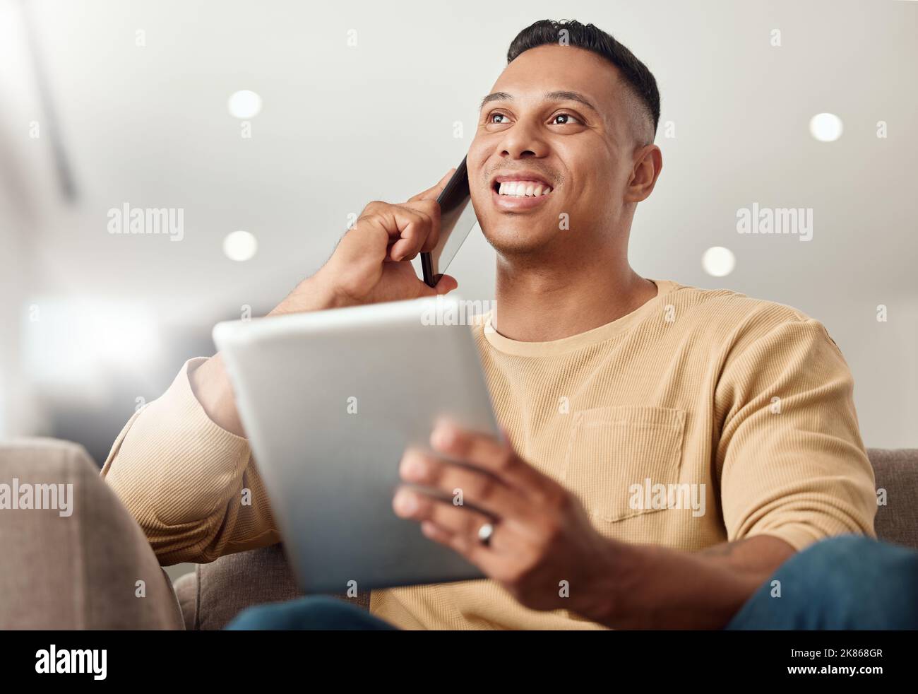Telefonanruf, Tablet und Mann vernetzen sich, sprechen und arbeiten im Internet vom Sofa in seinem Haus aus. Glücklich, denkend und junger Freiberufler sprechen Stockfoto