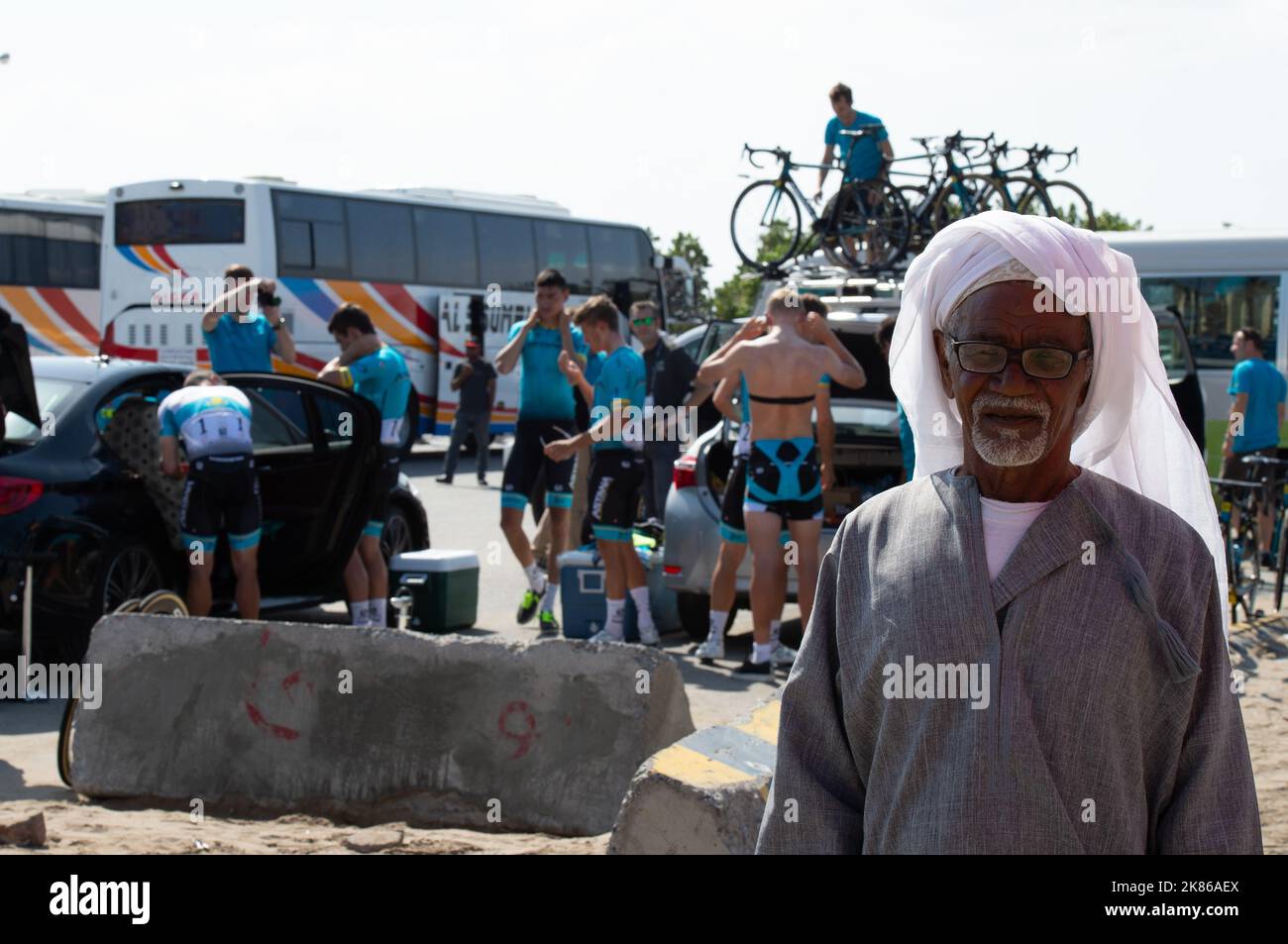 Ein lokaler Omani posiert für ein Foto unter den Fahrern, die sich auf die Etappe vorbereiten.Tour of Oman Etappe 1, Al Sawadi Beach bis Suhar Corniche. Stockfoto