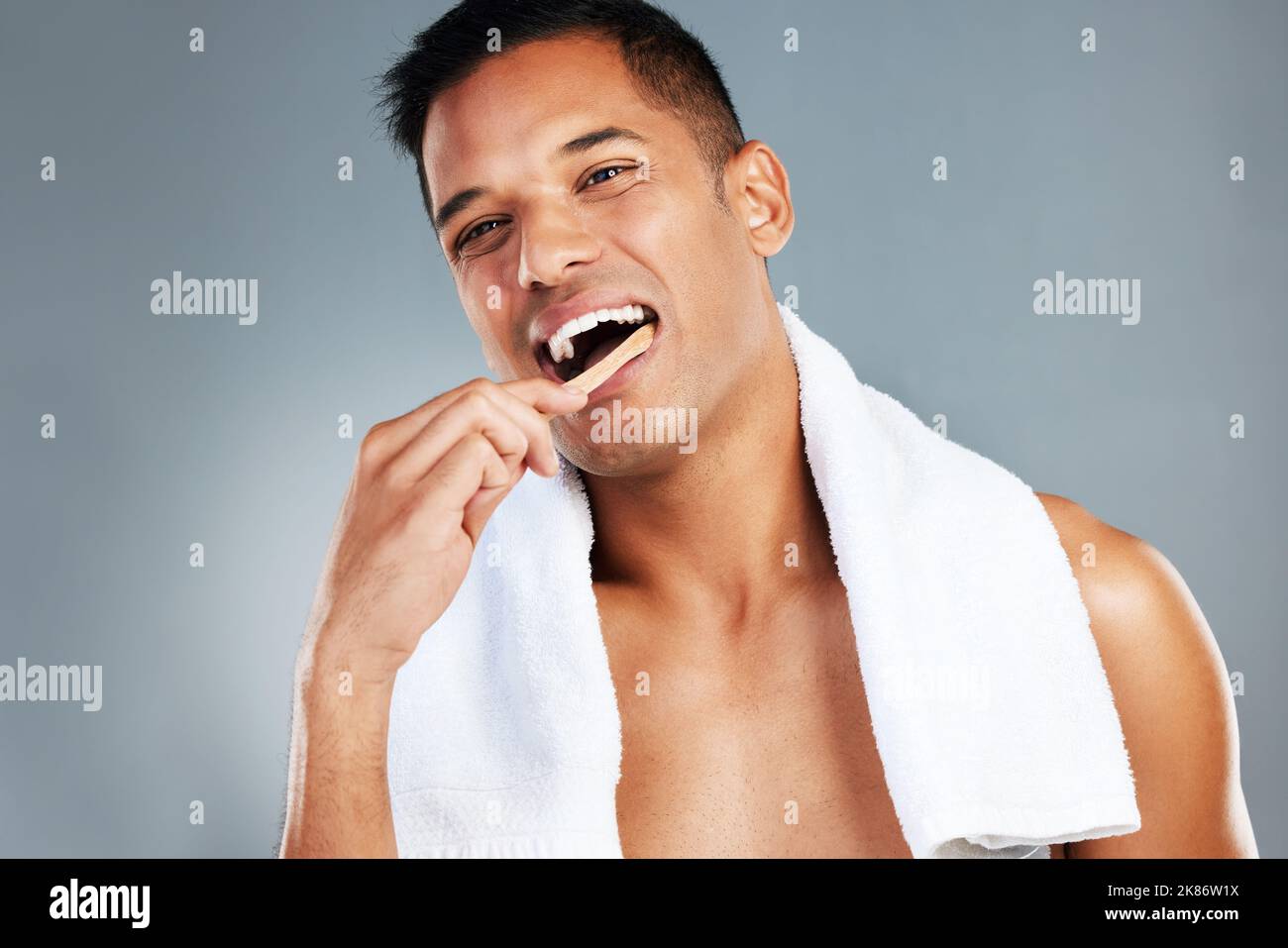 Mann, Zahnbürste und Zähne für die Zahnhygiene in sauber, frisch und waschen für die Gesundheitsversorgung vor einem grauen Studio Hintergrund. Porträt eines toothy männlichen Stockfoto