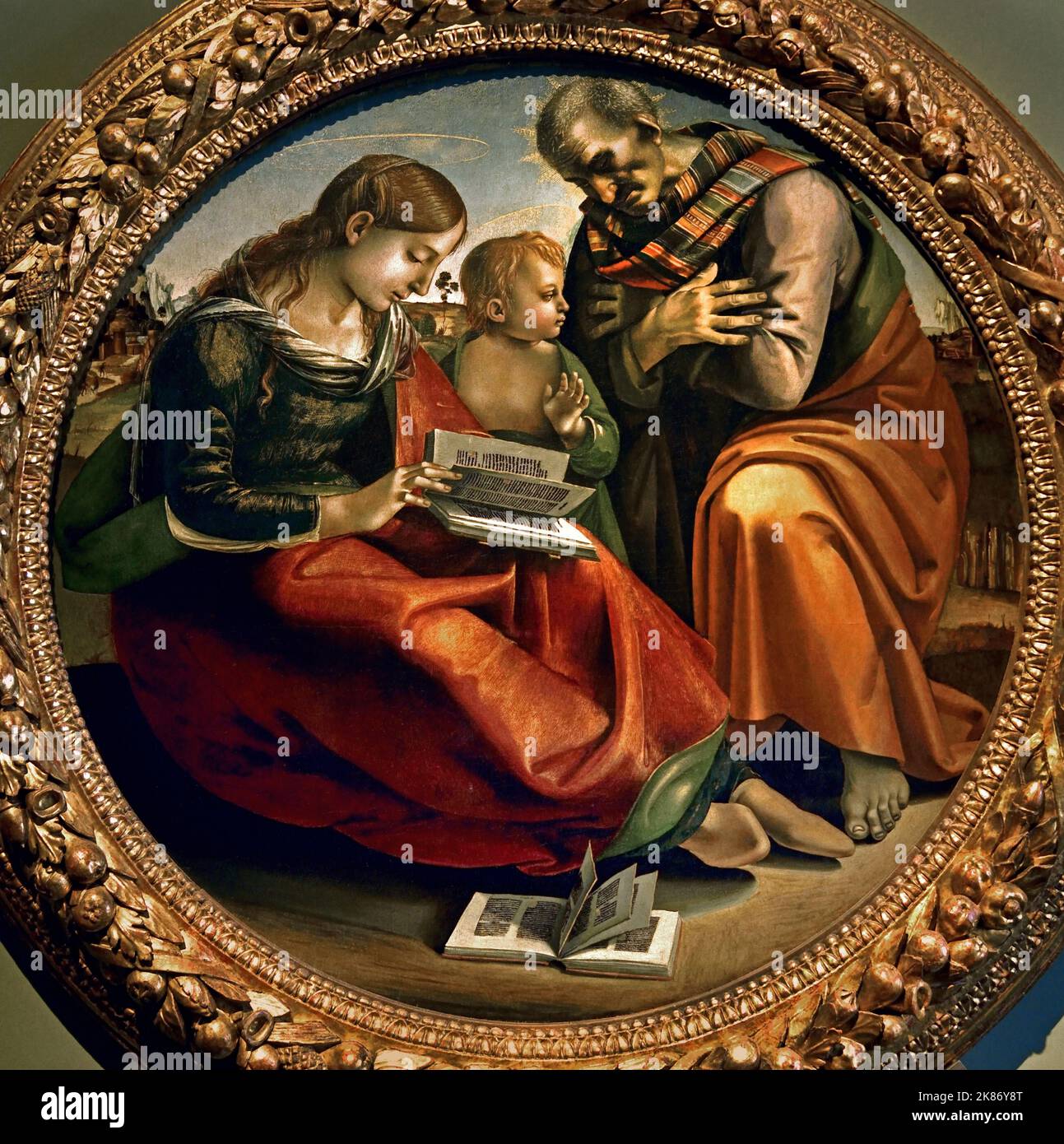 Heilige Familie, Luca Signorelli, (Cortona 1445 circa – 1523), Florenz, Italien. (Die Jungfrau, die sich durch einen perligen Teint und eine breite rote Tunika auszeichnet, will ein Buch lesen, während Christus den Blick auf den heiligen Josef richtet.) Stockfoto