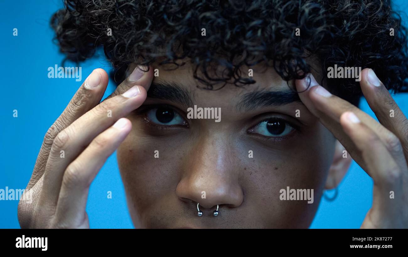 Beschnittene Ansicht eines jungen afroamerikanischen Mannes, der die Augenbrauen isoliert auf Blau berührt Stockfoto