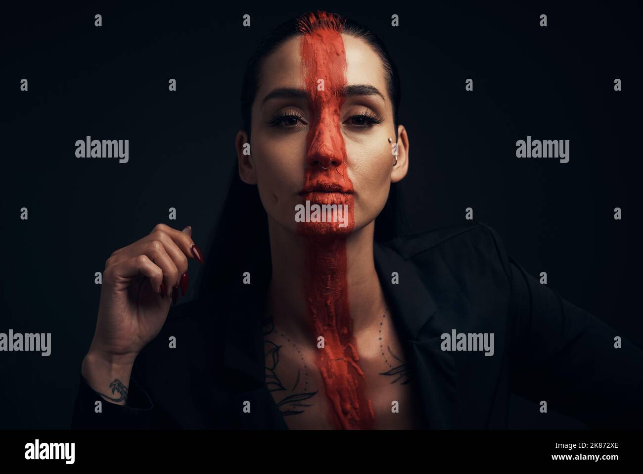 Kunst braucht keine Worte. Studioaufnahme einer jungen Frau, die mit Farbe auf ihrem Gesicht auf schwarzem Hintergrund posiert. Stockfoto