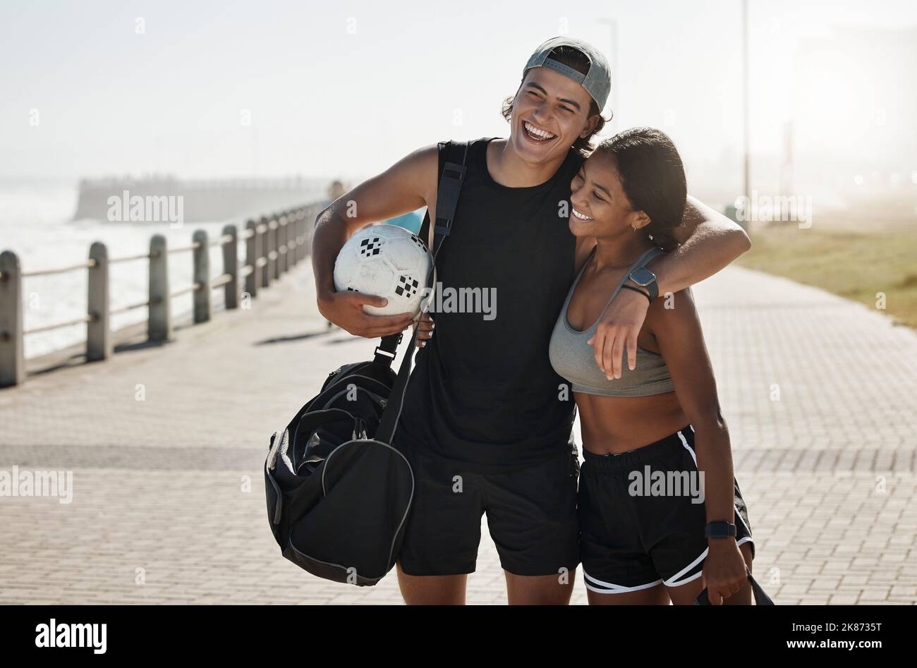 Paar, Sport und Fitness, Fußball und Fußball am Strand zusammen nach dem Training und Training. Junger Mann umarmt schwarze Frau, Sport im Freien und Sport Stockfoto