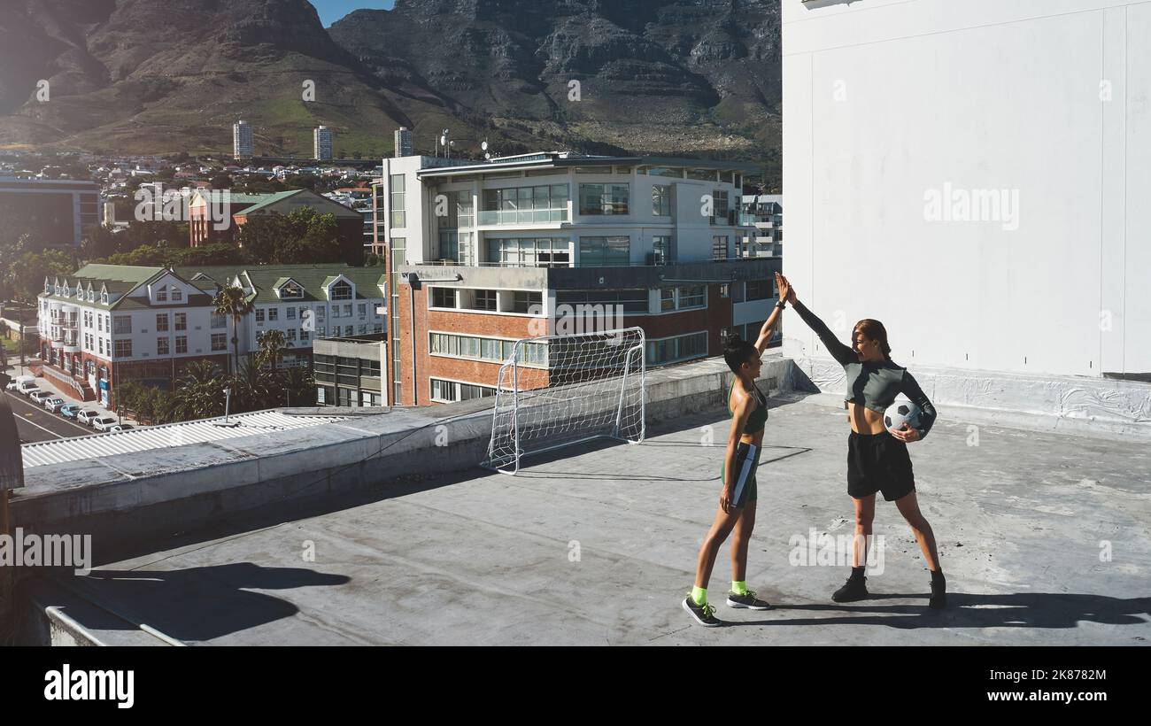 High Five für Motivation, Frauen und Fußball, Fitness und Freunde im Sporttraining, Teamübung im Stadtbild. Sportler mit Ball feiern Stockfoto