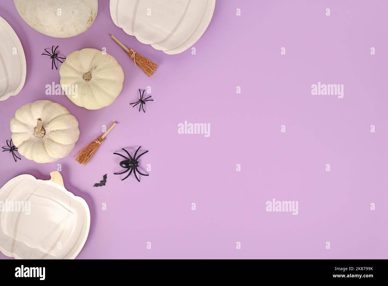 Halloween Party flach lag mit Kürbis geformten Tellern, Kürbissen, Hexenbesen, Spinnen und Särgen auf violettem Hintergrund mit Kopierraum Stockfoto