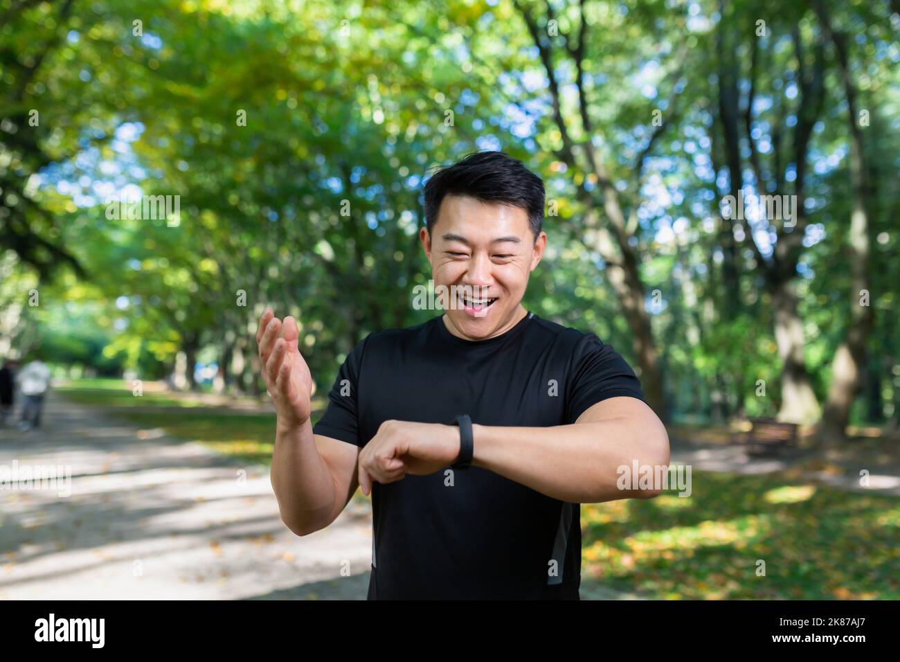 Sport kaukasischen Mann suchen Smart Uhr bei modernen Streckenläufer mit Smartwatch Fitness-Armband verwenden Portrait fit männlichen Athleten Überprüfung Ergebnis Joggen in Sportbekleidung auf der Straße städtischen Stadtpark im Freien Stockfoto