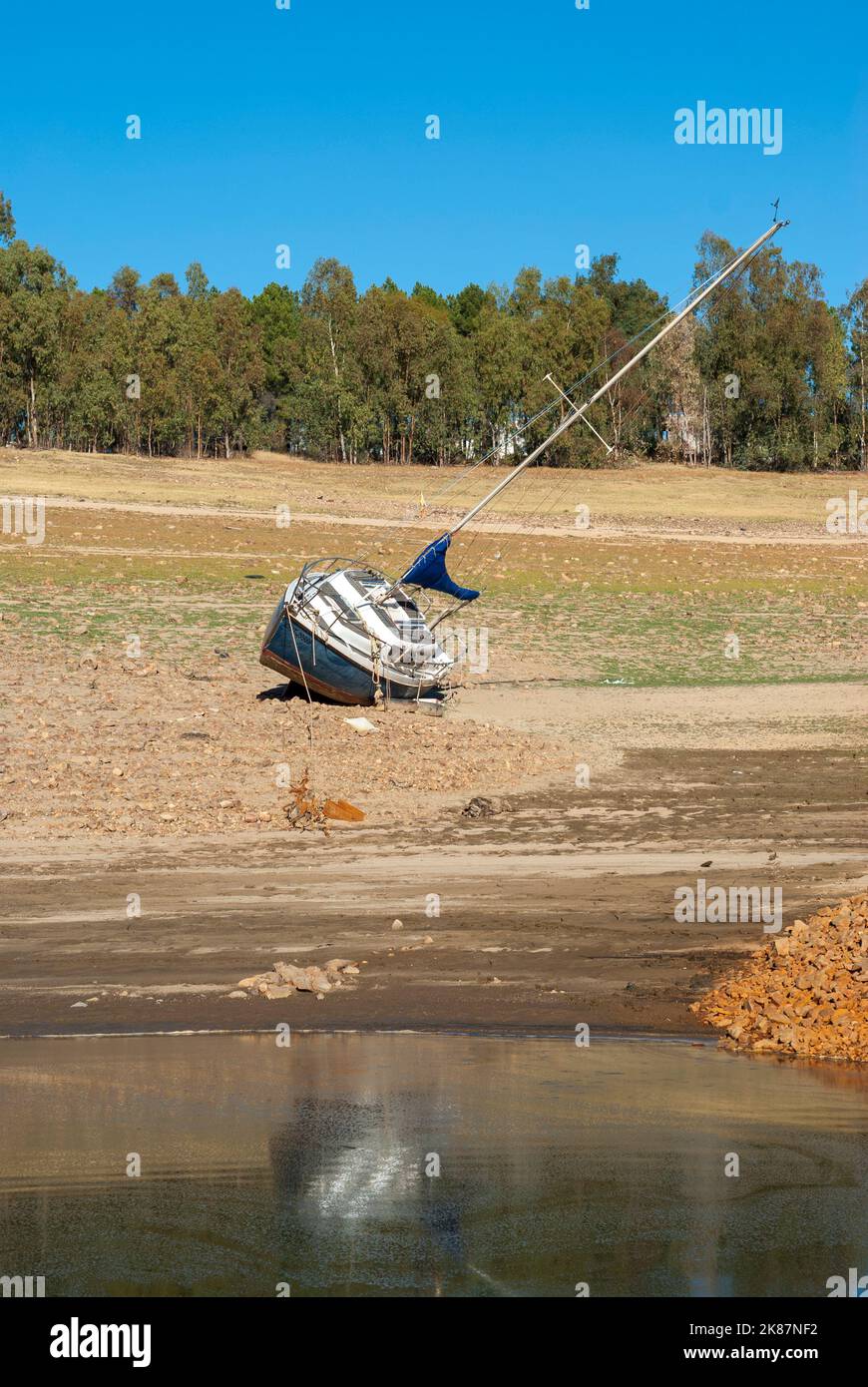 Schiff an Land weit vom Wasser wegen Dürre in senkrechter Höhe mit Reflexion im Wasser Stockfoto