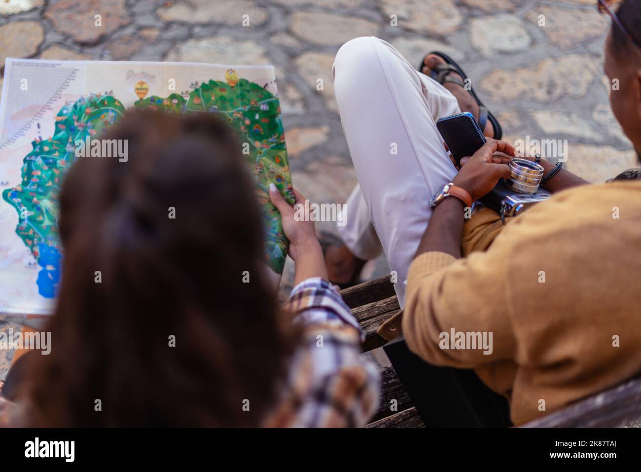 Ein Mann sitzt während einer Pause am Telefon. Seine Freundin sucht auf der Karte nach einem nächsten Reiseziel Stockfoto