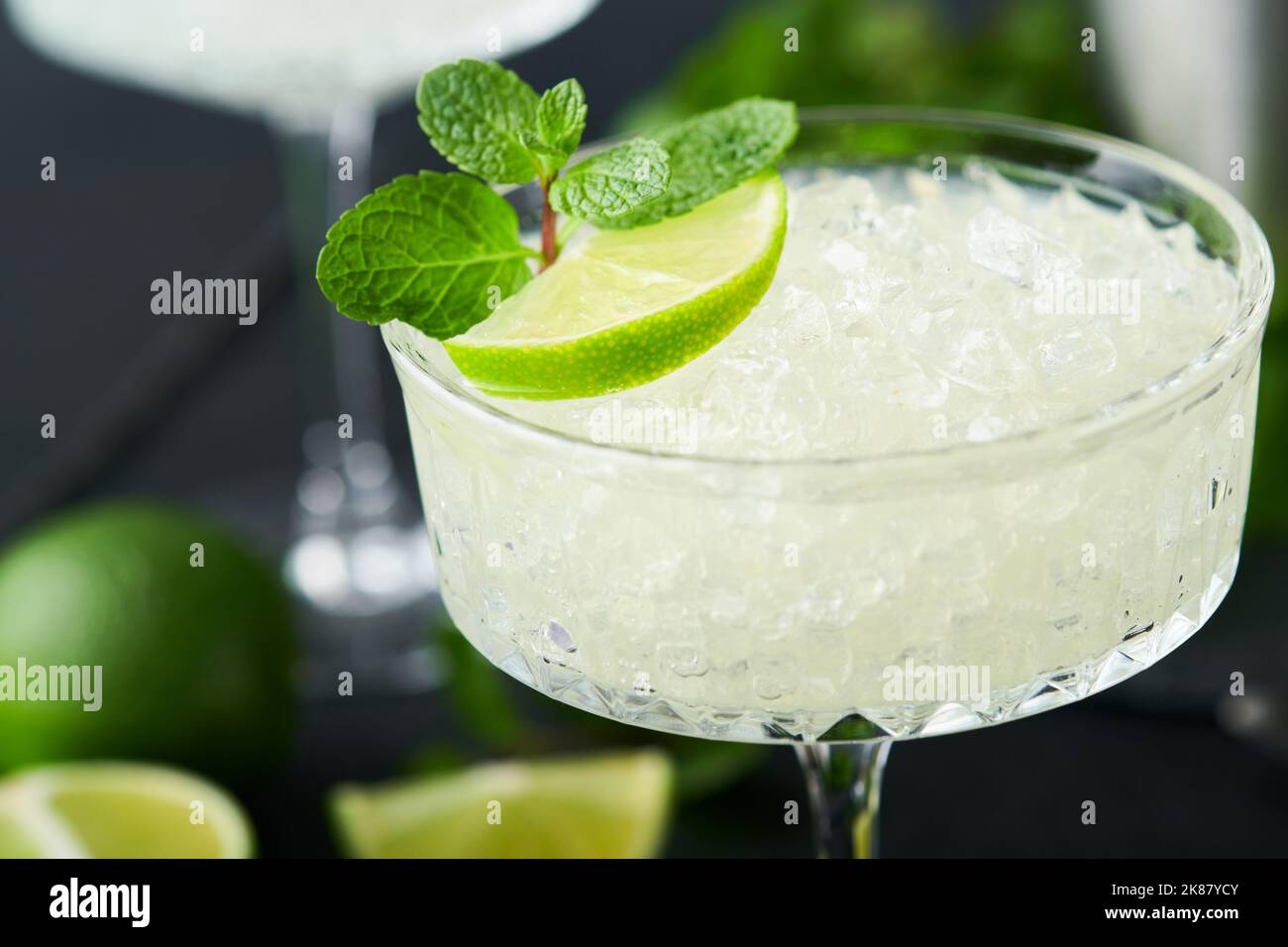 Margarita Cocktail mit Limette, Tequila, Minze und Eis auf dunklem Tisch mit erstaunlicher Hintergrundbeleuchtung, Kopierraum. Klassischer Margarita- oder Daiquiry-Cocktail. Barkarte Stockfoto