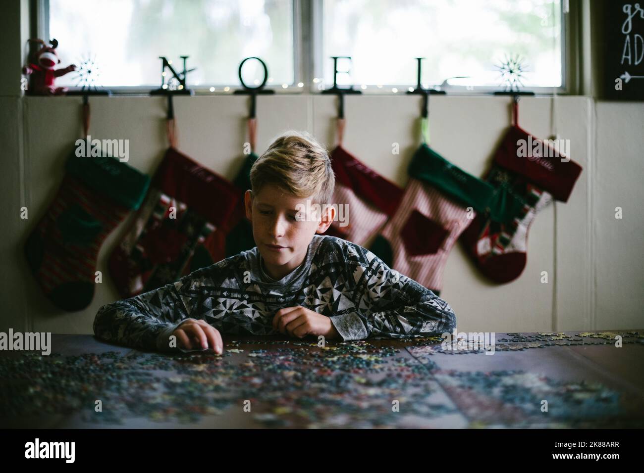 Junge Puzzle vor Strümpfen und weihnachtsdekorationen Stockfoto