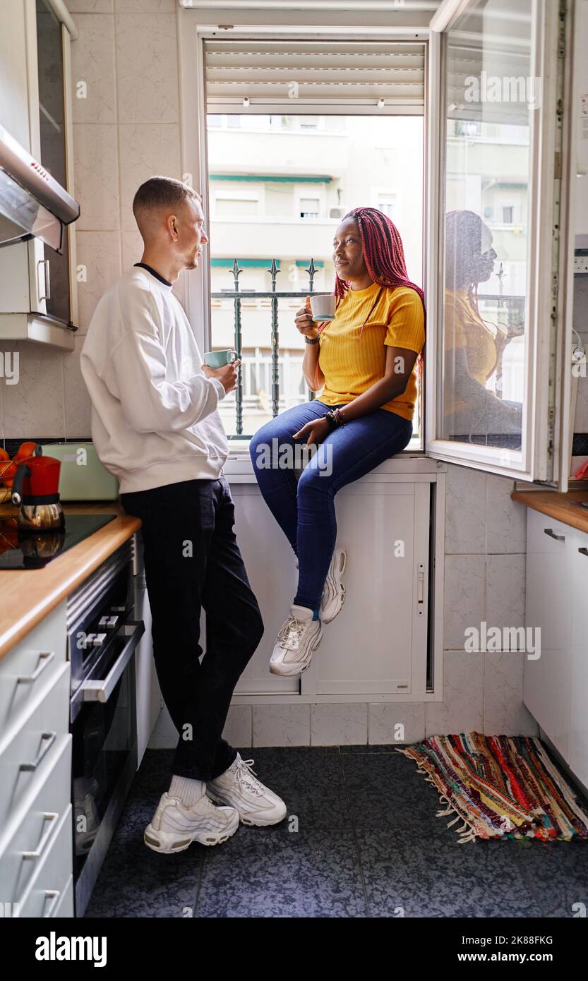 Glückliches multiethnisches Paar, das zu Hause Kaffee trinken kann Stockfoto