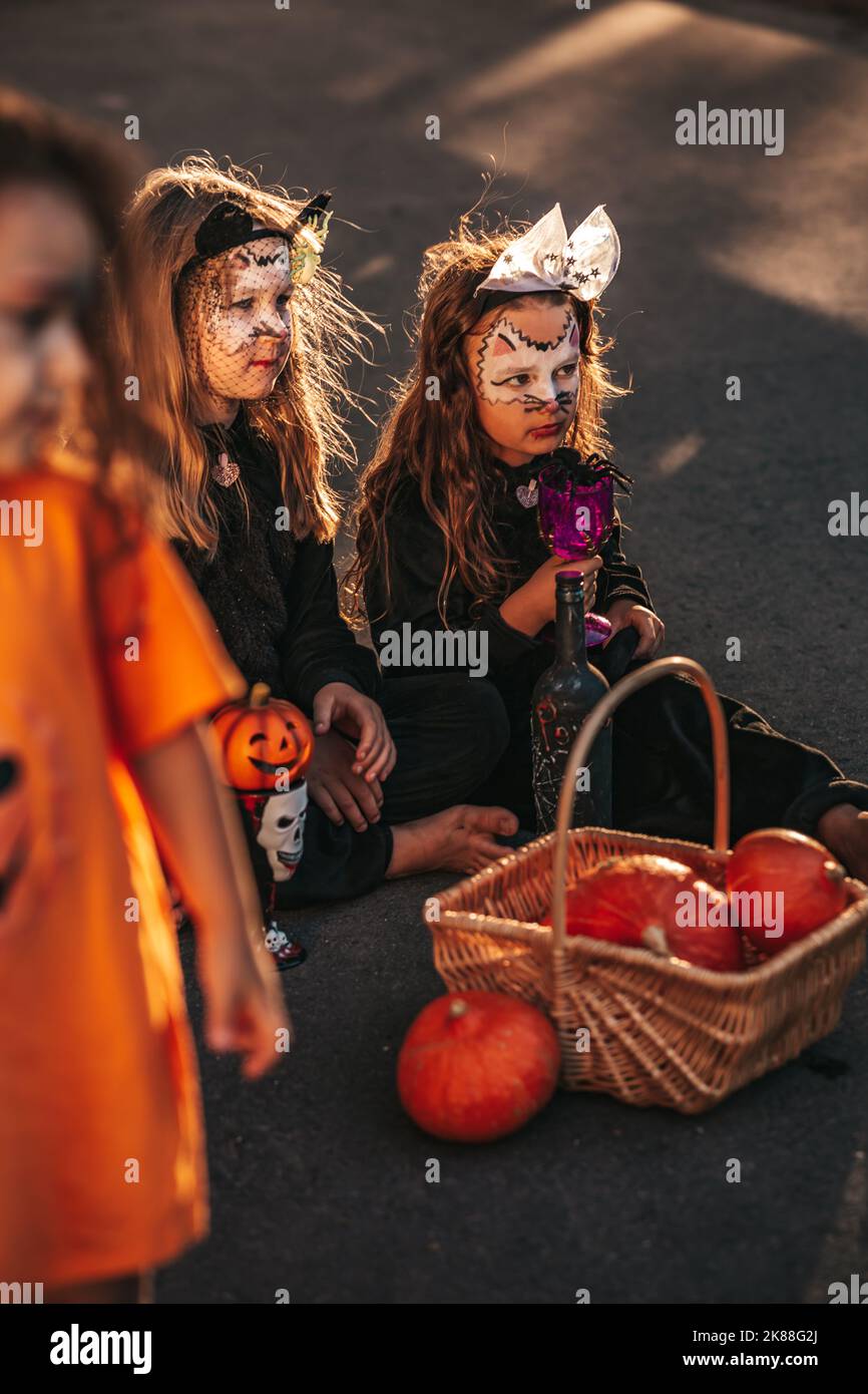 Zwei kleine Mädchen, die als schwarze Katzen gekleidet sind, feiern eine Halloween-Party Stockfoto