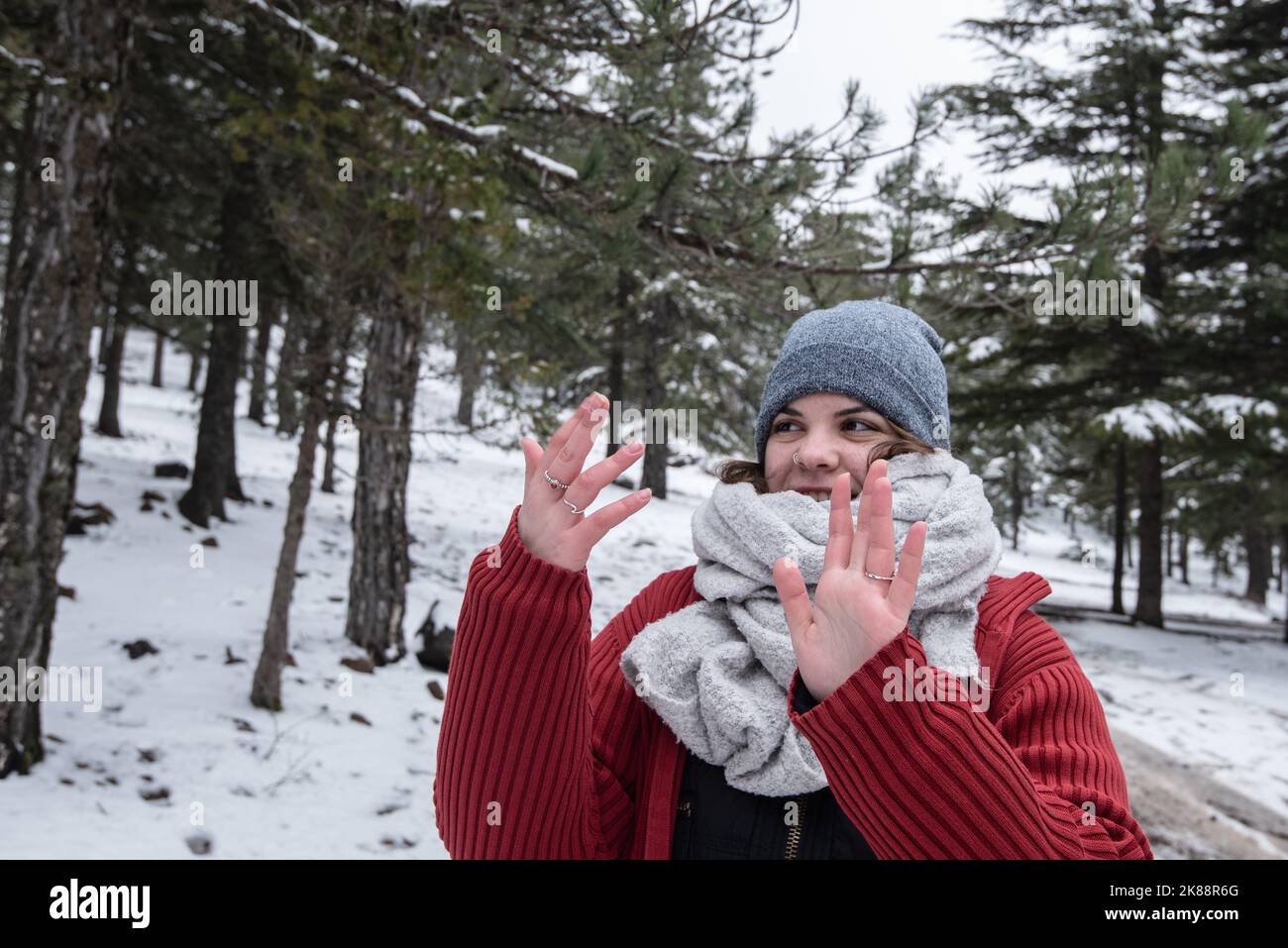 Junge, fröhlich lächelnde Frau spielt auf Schnee im Wald. Winter im Troodos Gebirge Zypern Stockfoto
