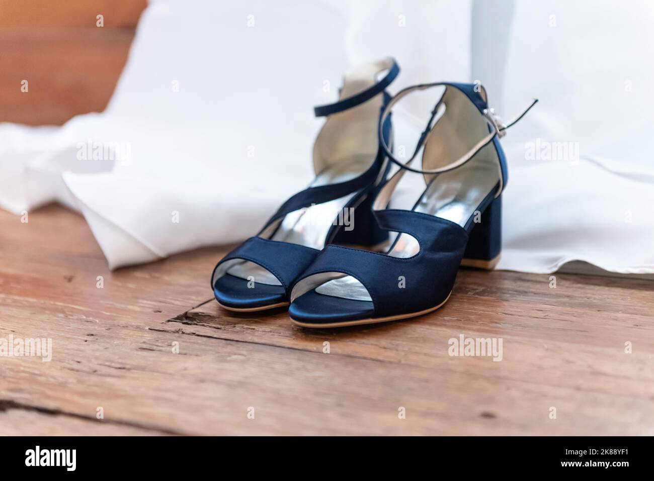 Offene Schuhe der Braut werden ausgeschnallt und neben dem Hochzeitskleid angelegt. Stockfoto