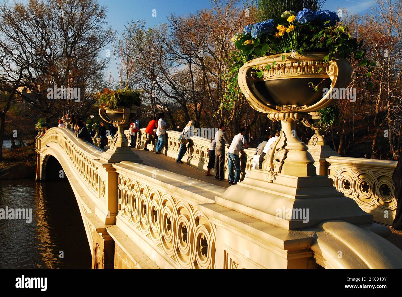 Die Menschen genießen einen warmen Frühlingstag und bewundern den Blick auf den Central Park in New York von der Bow Bridge aus Stockfoto