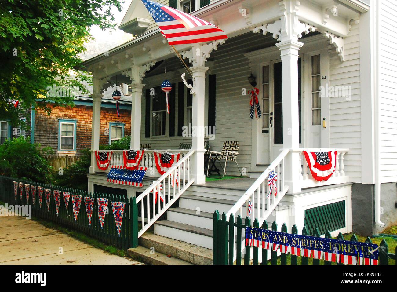 Am 4. Juli fliegt eine amerikanische Flagge von der Veranda eines historischen Hauses in Bristol, Rhode Island Stockfoto