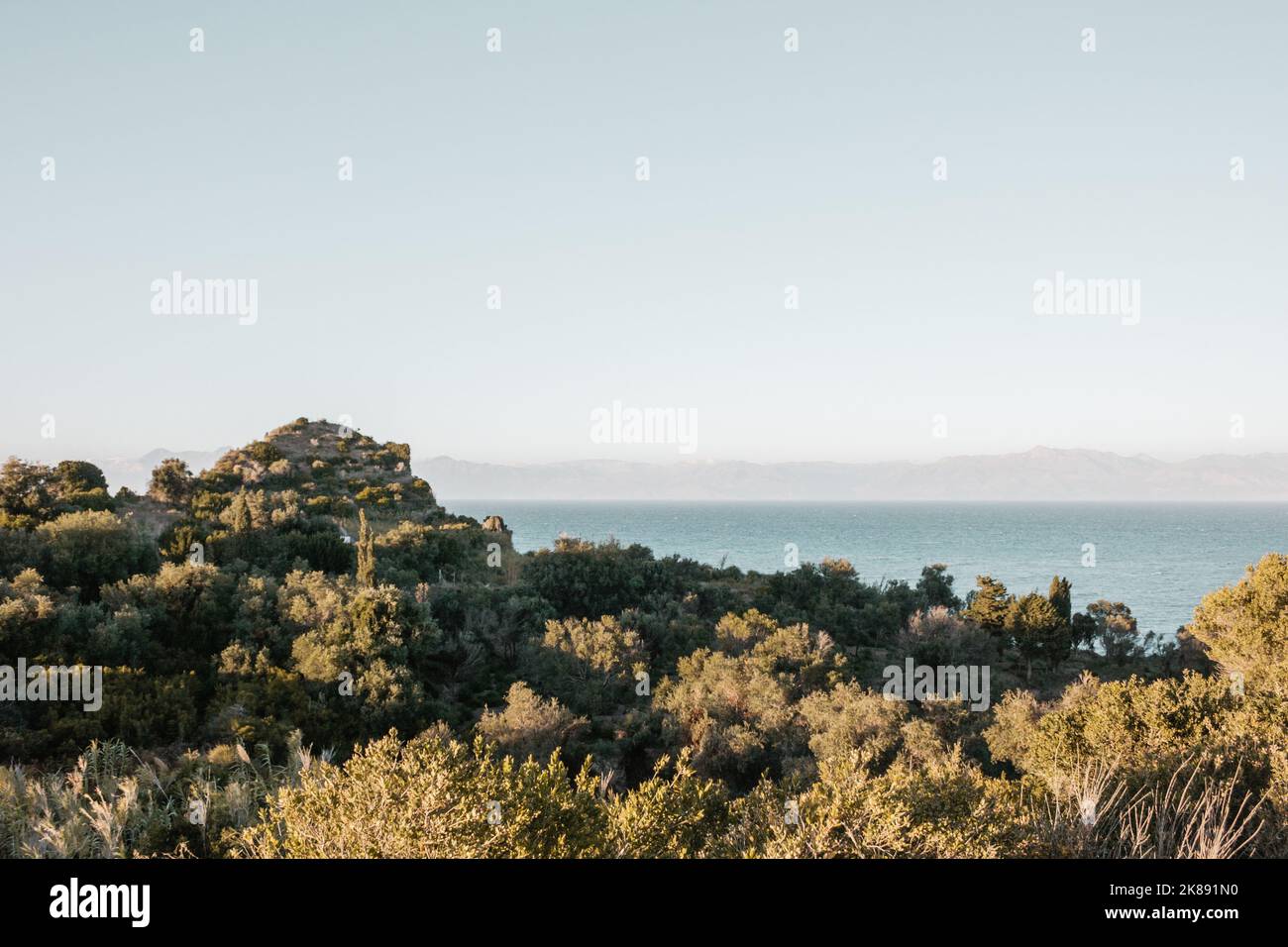 Schöne Aussicht auf das Meer in Griechenland mit Bergen am Horizont und grünen Büschen und Bergen im Vordergrund. Stockfoto