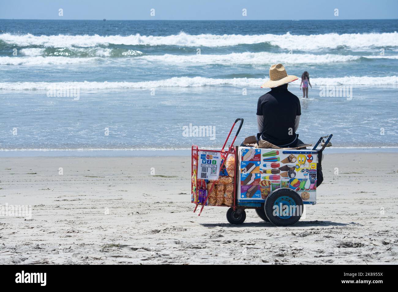 Ein Eisverkäufer sitzt auf seinem Wagen und schaut auf das Meer Stockfoto