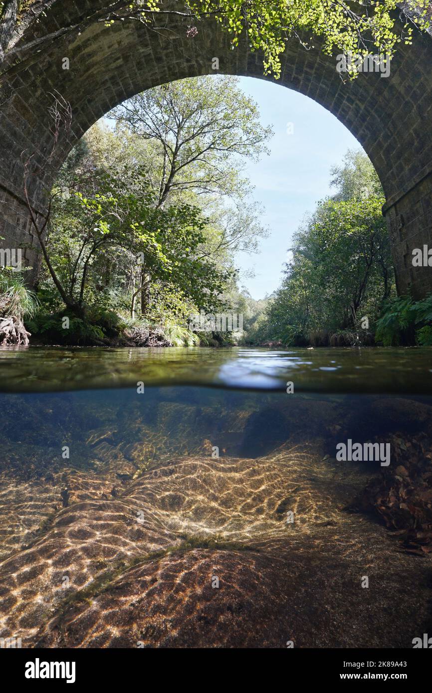 Fluss unter dem Bogen einer Steinbrücke, Split-Level-Ansicht über und unter der Wasseroberfläche, Spanien, Galizien, Fluss Oitaven, Provinz Pontevedra Stockfoto