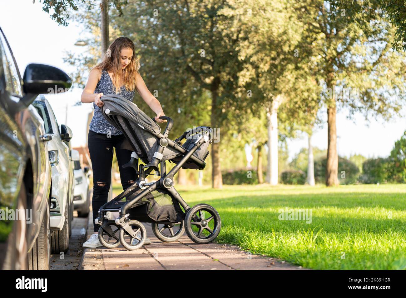 Mutter bereitet den Kinderwagen nach dem Parken im Park vor Stockfoto