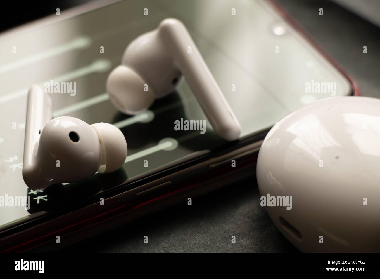Kabellose weiße Kopfhörer und ein Equalizer im Telefon, Online-Musik im  Telefon und Lieder Stockfotografie - Alamy