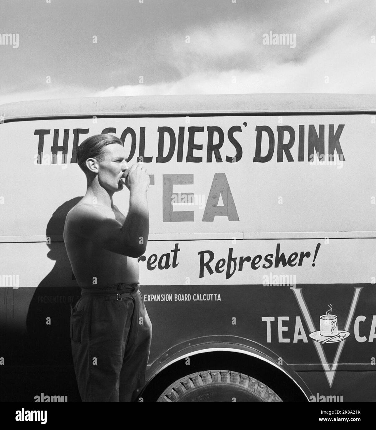Cecil Beaton - General India 1944: Ein Soldat, der am Flughafen von Kalkutta neben einem mobilen Teewagen des Roten Kreuzes eine Tasse Tee trinkt. Stockfoto