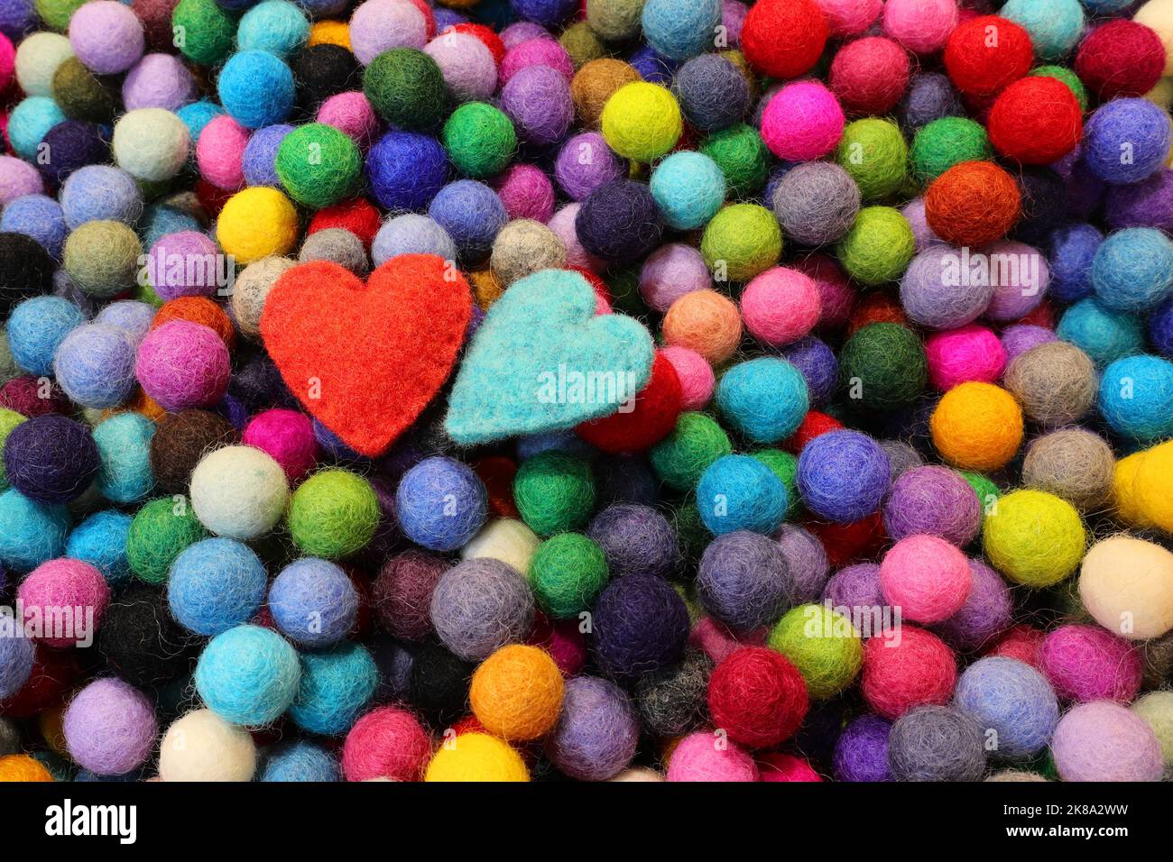 Kugeln aus geschnitzter Filzwolle und zwei blauen und roten Herzen Stockfoto