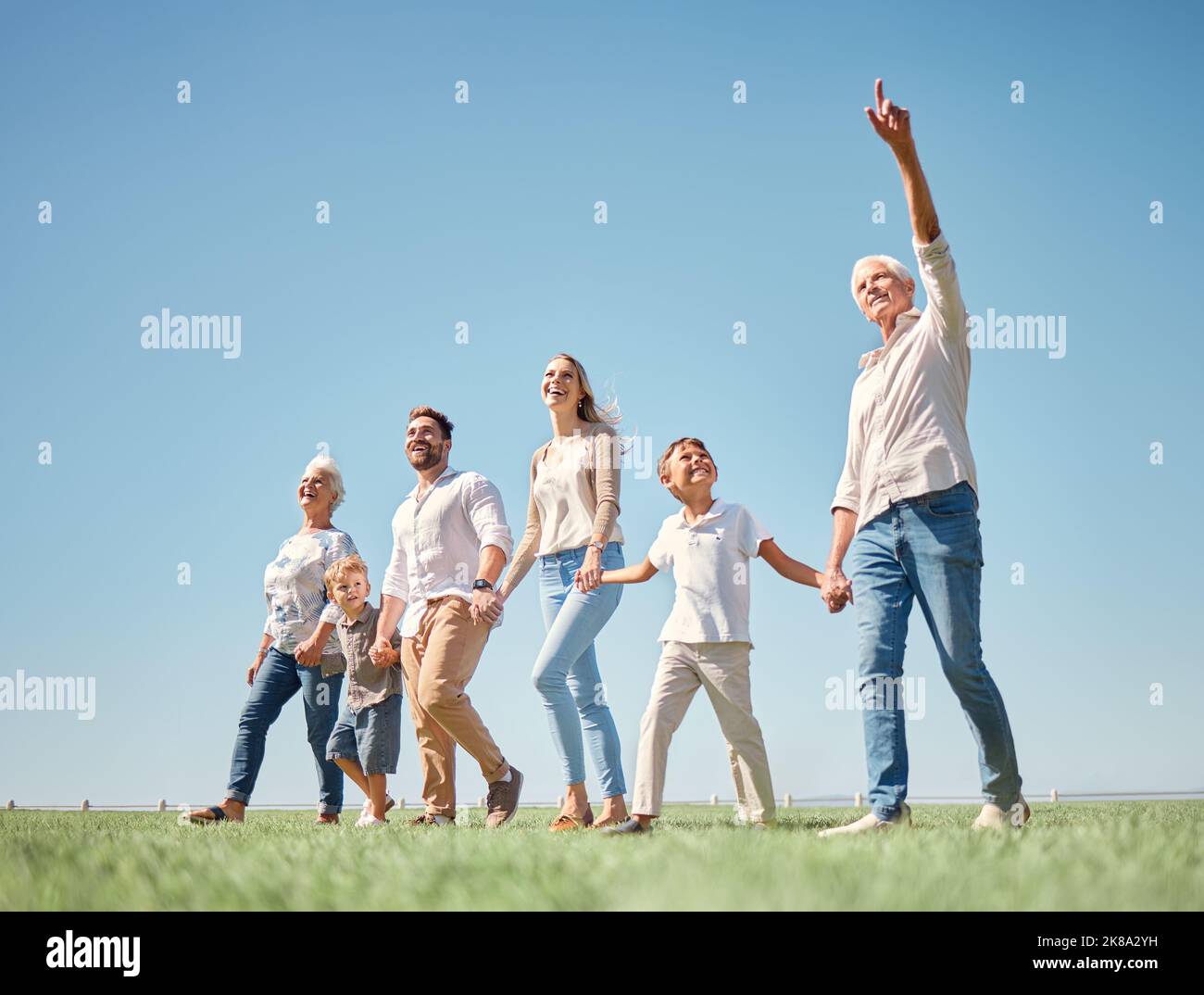 Familie, Wandern und Natur zusammen mit Feld, Gras und Sonnenschein während des Urlaubs. Mama, Papa und Kinder gehen im Frühling in grünen Wäldern oder im Park Stockfoto