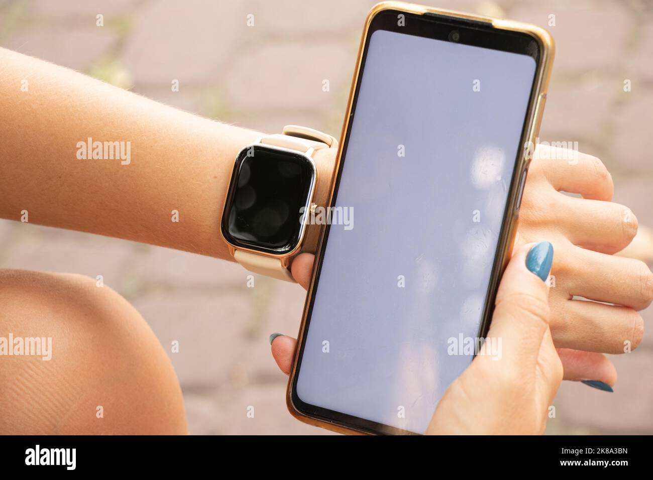 Smart Watch und ein Telefon mit einem weißen Bildschirm in den Händen eines Mädchens im Park, neue Technologien und Menschen, eine Uhr und ein Telefon Stockfoto