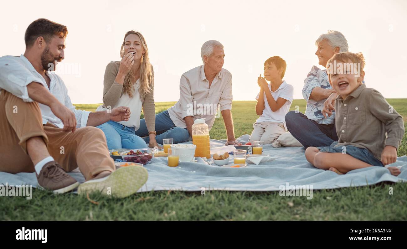 Liebe, Picknick und Familienglück mit Menschen lächeln und entspannen in einem Park oder Feld, Kleben und Spaß haben. Glückliche Kinder genießen den Wochenendurlaub mit Stockfoto