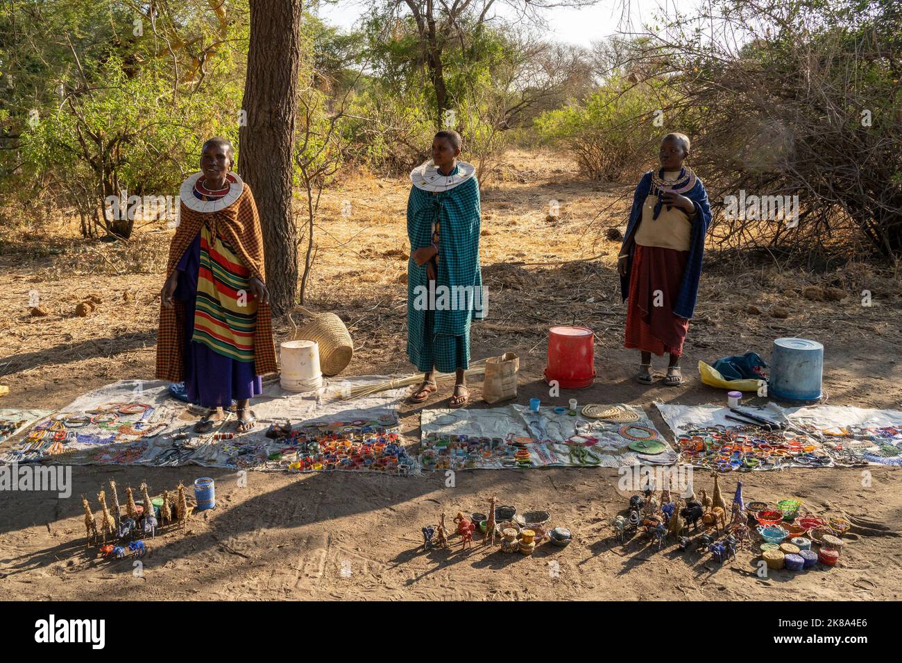 Tarangire, Tansania - 12.. Oktober 2022: Masai-Frauen verkaufen handgemachten Schmuck und Ornamente am Straßenrand im Morgengrauen. Stockfoto
