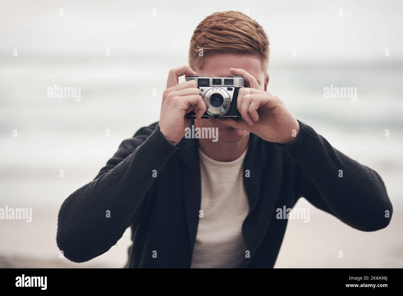 Machen Sie ein Foto, es dauert länger. Ein Mann, der mit seiner Kamera am Strand fotografiert. Stockfoto