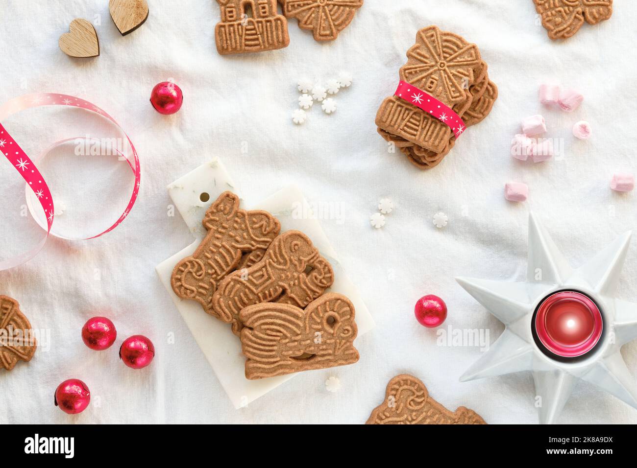 SPECULOOS oder Spekulatius, Weihnachtskekse, Schokoladenkugeln und Band auf weißer textiler Tischdecke. Traditionelle deutsche Süßigkeiten, Kekse für Weihnachten, Stockfoto