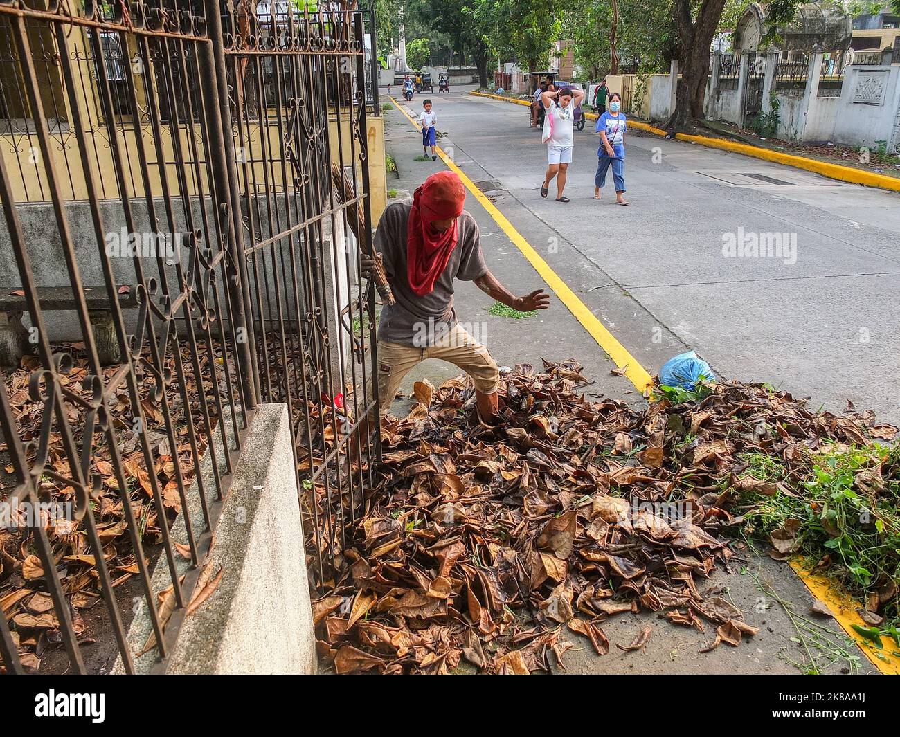 Ein Friedhofswärter, der einen Besen hält, versucht vor Allerheiligen, dicke, getrocknete Blätter in einem verlassenen Grab zu entfernen. Vor der Allerheiligen-Feier strömen die Filipinos zum North Cemetery in Manila. Allerheiligen ist eine christliche Feierlichkeit, oder würdevolle Erinnerung, die die Ehre aller Heiligen der Kirche feiert, ob bekannt oder unbekannt viele nutzen den Feiertag, um an verstorbene geliebte Menschen zu erinnern. Blumenhändler präsentieren ihre Waren, während Handwerker Grabstein auf Anfrage von Kunden schnitzen. (Foto von Josefiel Rivera/SOPA Images/Sipa USA) Stockfoto