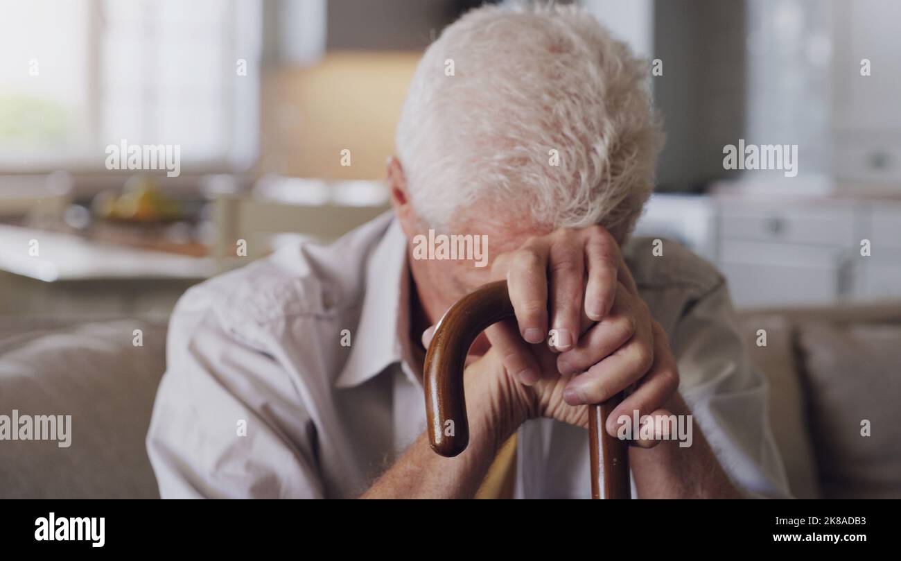 Depression kommt von zu viel Zeit im Kopf. Ein älterer Mann sitzt allein auf dem Sofa zu Hause und fühlt sich deprimiert, während er seine hält Stockfoto