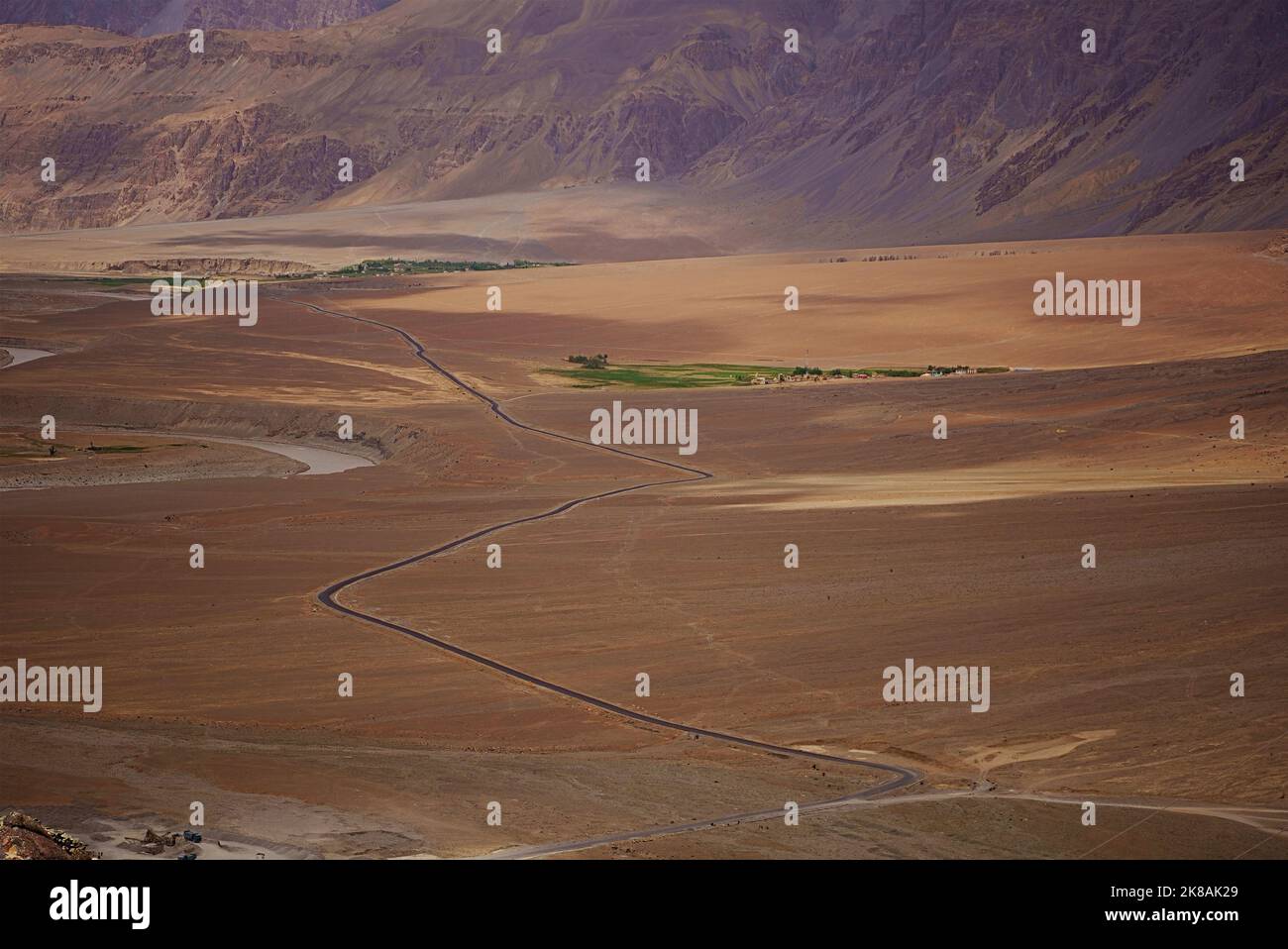 Luftaufnahme von oben Straße Schnitt durch grafische Landschaft trockenen kalten Wüste kargen Bergen kontrastierenden grünen Feld Farmen im Flusstal Stockfoto