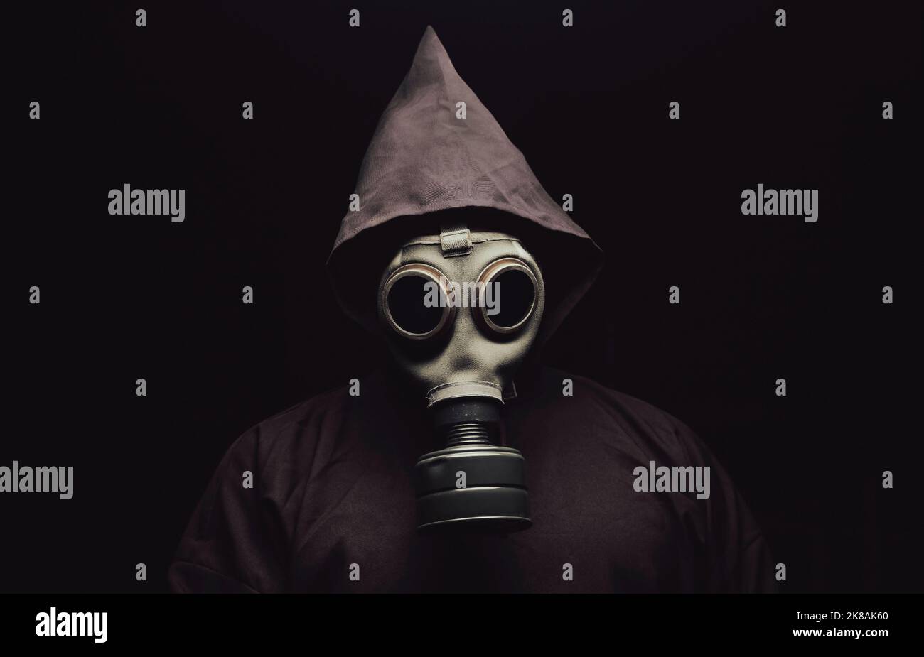 Ein gruseliger Mann in einem Umhang, der eine Gasmaske trägt. Dunkler Hintergrund. Stockfoto