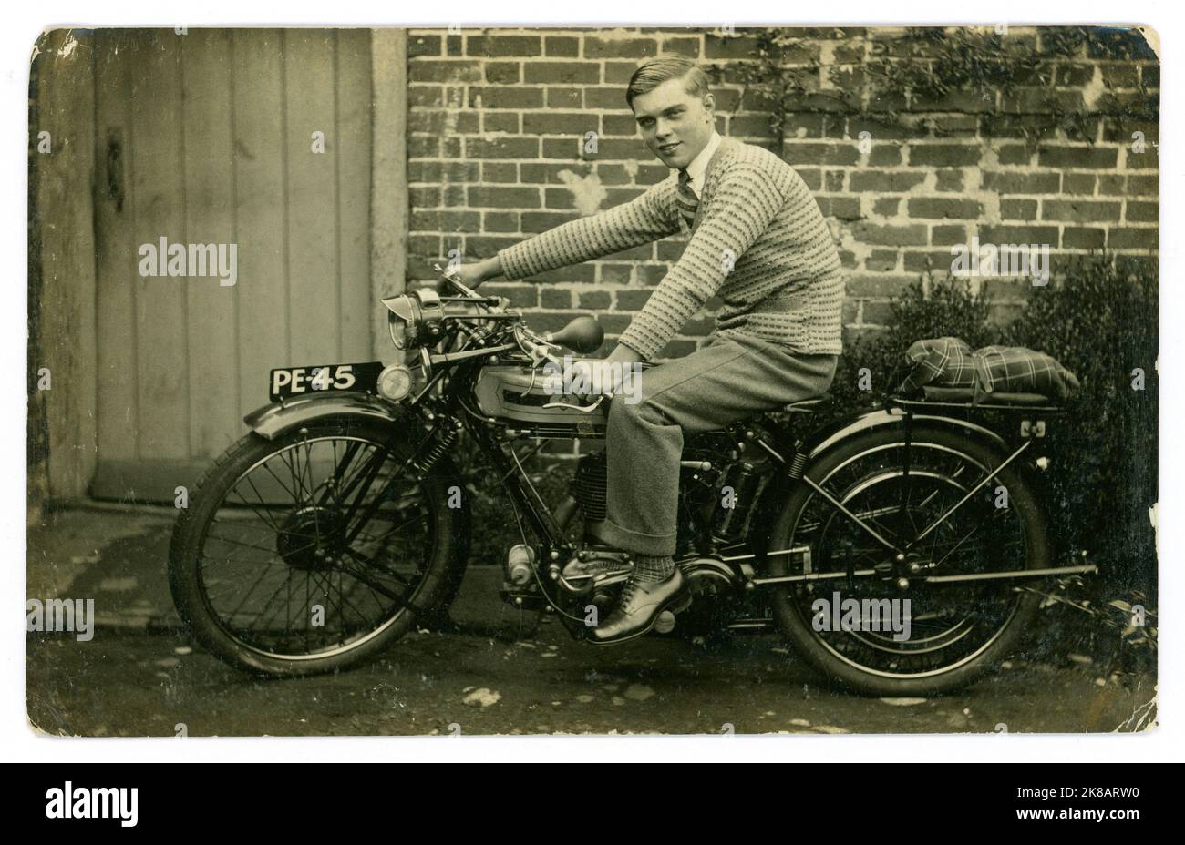 Original-Postkarte aus der Zeit der 1920er Jahre mit glücklichem stolzen jungen Mann oder späten Teenagern, sitzend auf einem brandneuen Triumph-Motorrad, Guildford-Registrierung, Surrey, England, Großbritannien Ende 1920 Stockfoto