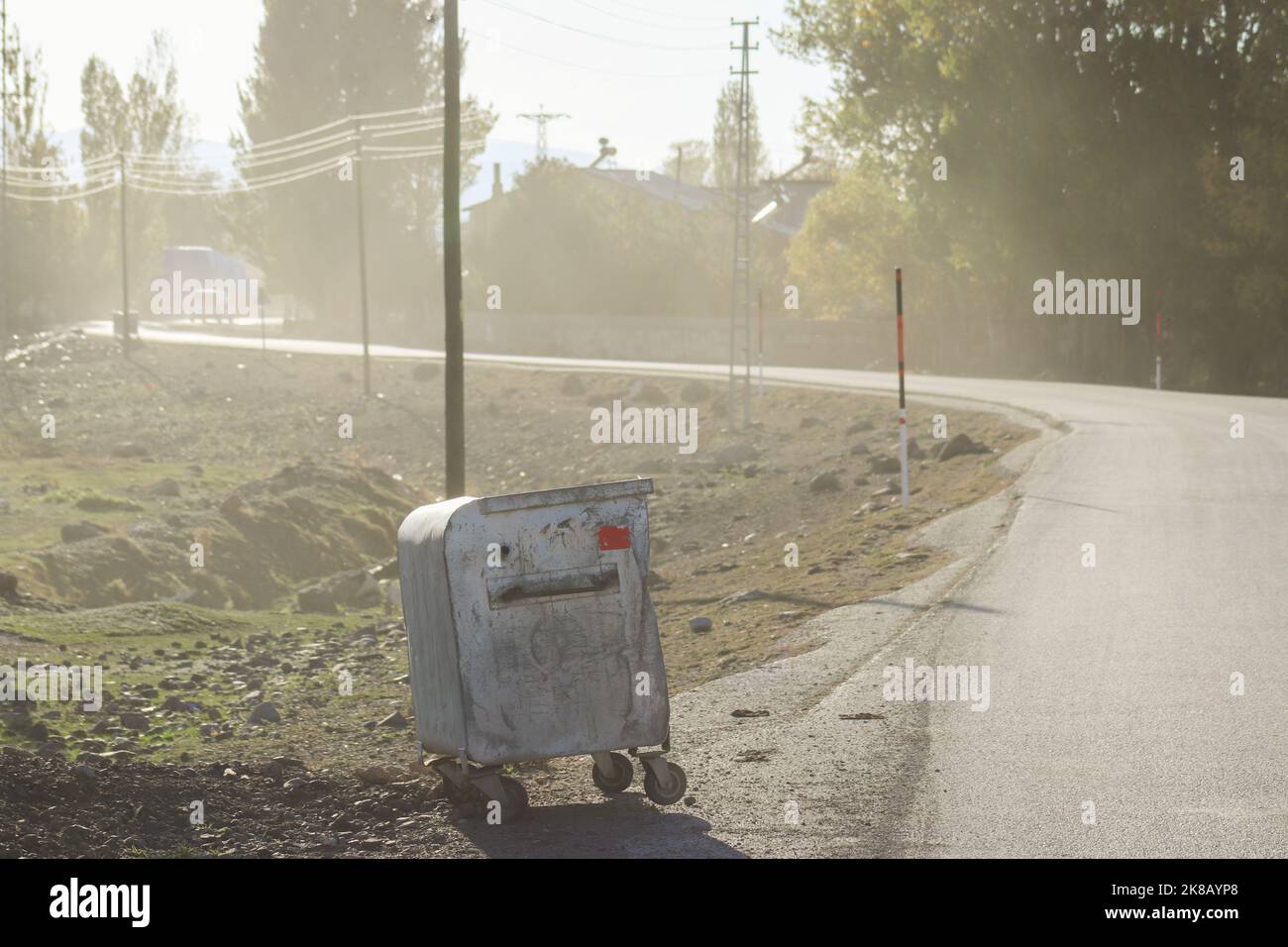 Ein Müllcontainer, der bei sonnigem Foggy am Straßenrand steht. Stockfoto