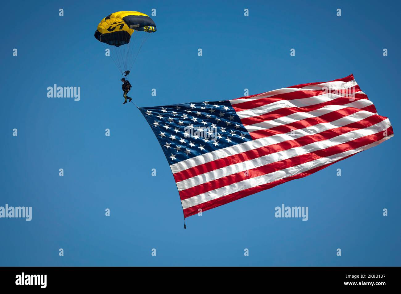 Ein Mitglied des Fallschirmsprungteams der US Navy Leap Frogs bringt die amerikanische Flagge zur Miramar Airshow 2022 in San Diego, Kalifornien. Stockfoto