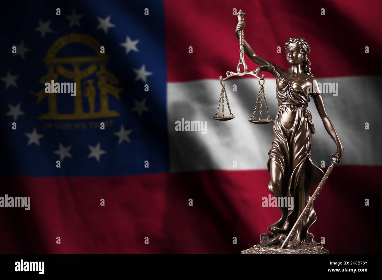 Georgia US-Staatsflagge mit Statue der Justizdame und Justizwaagen in dunklem Raum. Konzept von Urteil und Bestrafung, Hintergrund für Jurythemen Stockfoto