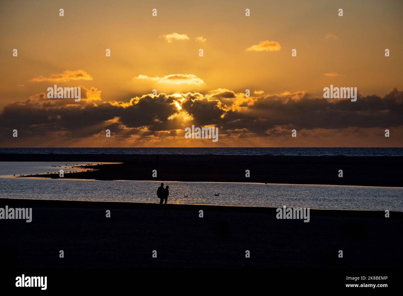 Silhouette von Verliebten unter der untergehenden Sonne in Kijkduin, Zandmotor, Niederlande. Stockfoto