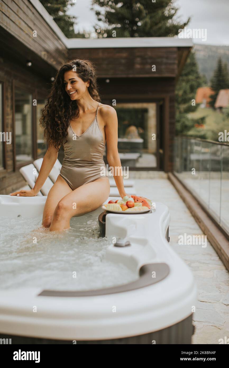 Attraktive junge Frau, die im Urlaub im Whirlpool im Freien genießt Stockfoto