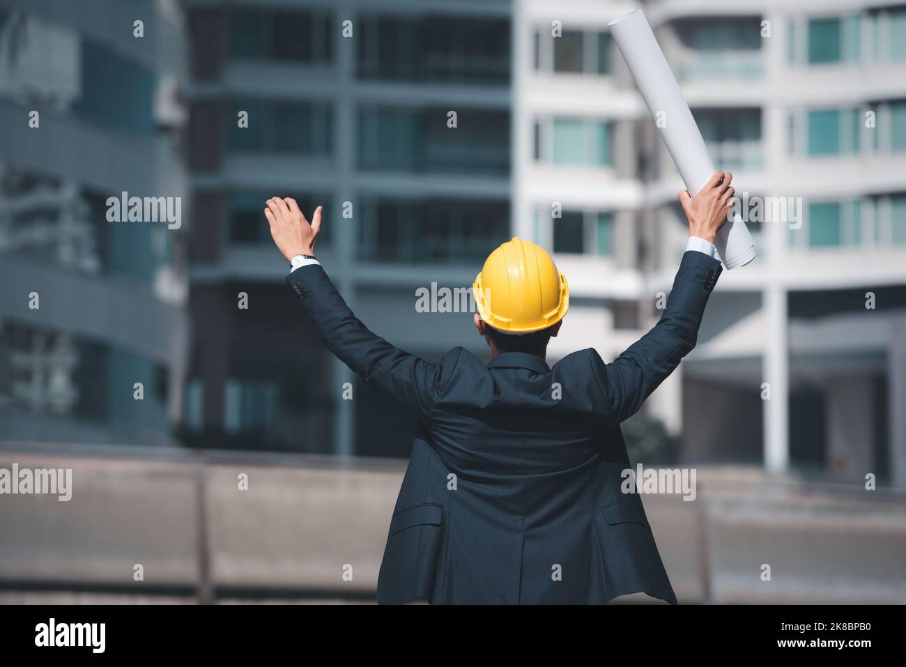 Der Architekturingenieur hob die Hände und hielt den Bauplan, um den Erfolg der Baustelle zu zeigen. Stockfoto