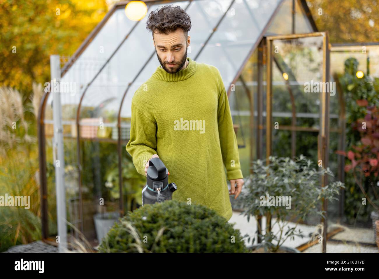 Guy schneidet einen runden Busch mit einer Schere Stockfoto