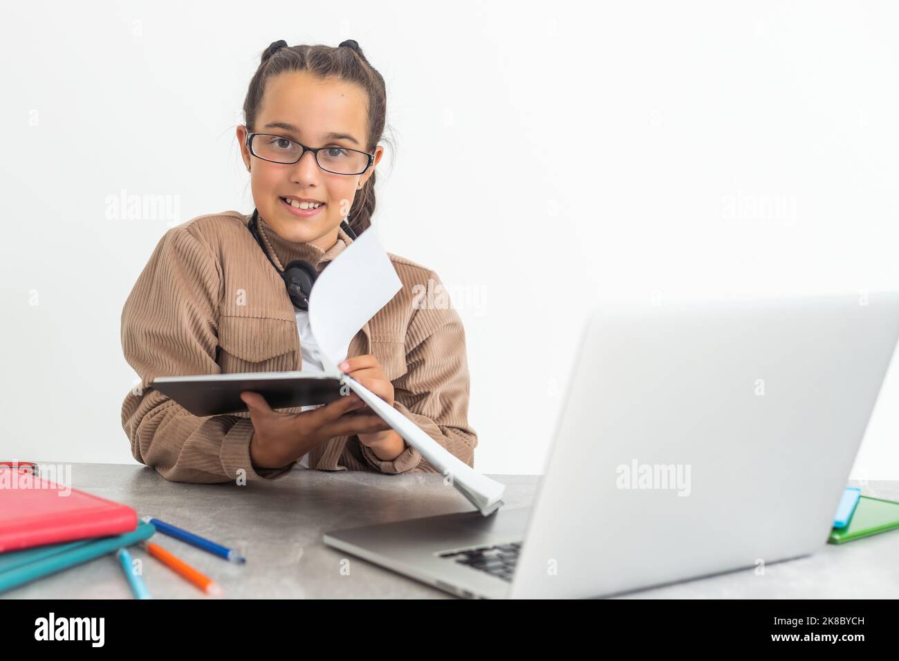 Lächelnd kleine kaukasische Mädchen in Kopfhörer handschreiben Studie online mit Laptop zu Hause, nette glückliche kleine Kind in Kopfhörer nehmen Internet-Web-Lektion Stockfoto