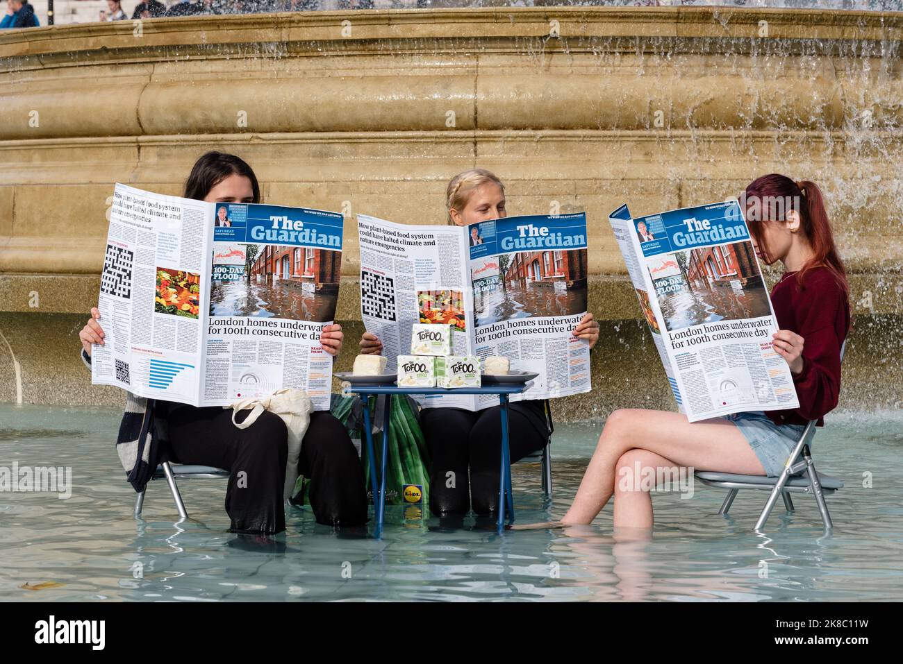 London, Großbritannien. 22. Oktober 2022. Tierrechtsaktivisten Animal Rebellion färbt Trafalgar Square-Brunnen grün, während sie an einem Tisch sitzen und eine Zeitung lesen. Der Protest folgt auf Kommentare der ehemaligen Innenministerin Suella Braverman, die die Aktivisten als "Hüterlesung, Tofu-Essen, Wokerati" bezeichnete. Die Aktivisten fordern eine Transaktion zum pflanzenbasierten Ernährungssystem und für die Regierung, das Land zurückzugeben. Quelle: Andrea Domeniconi/Alamy Live News Stockfoto
